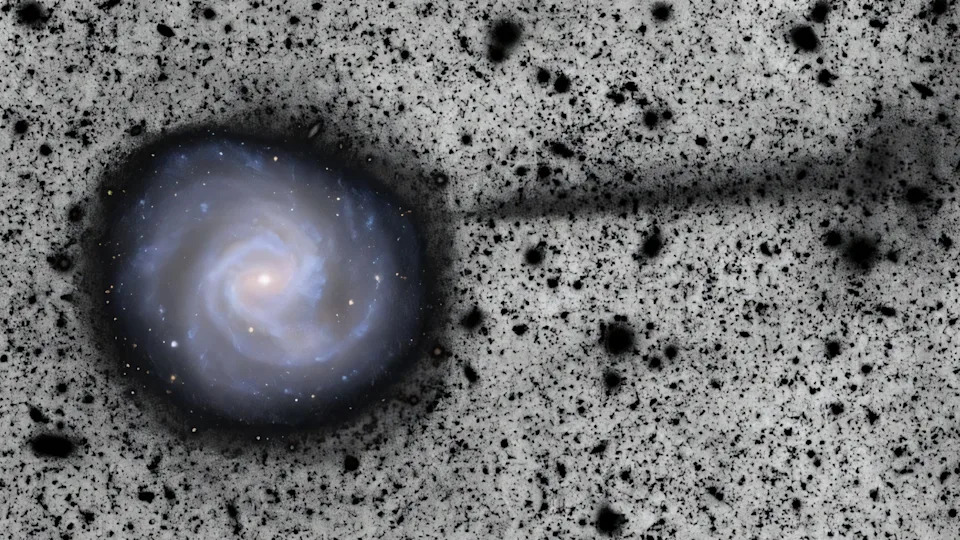 An image of a rotating galaxy on a black and white background with a layer of black objects appearing in the galaxy.