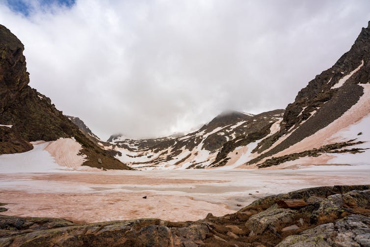 a snowy mountain valley, with orange dust