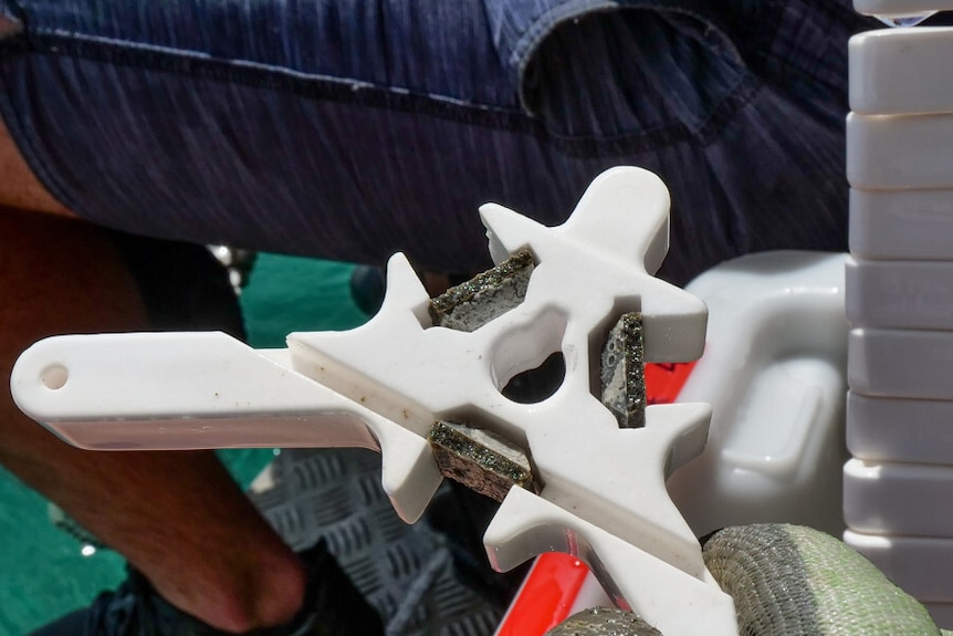 A white triangular shaped device with three small plates inside.