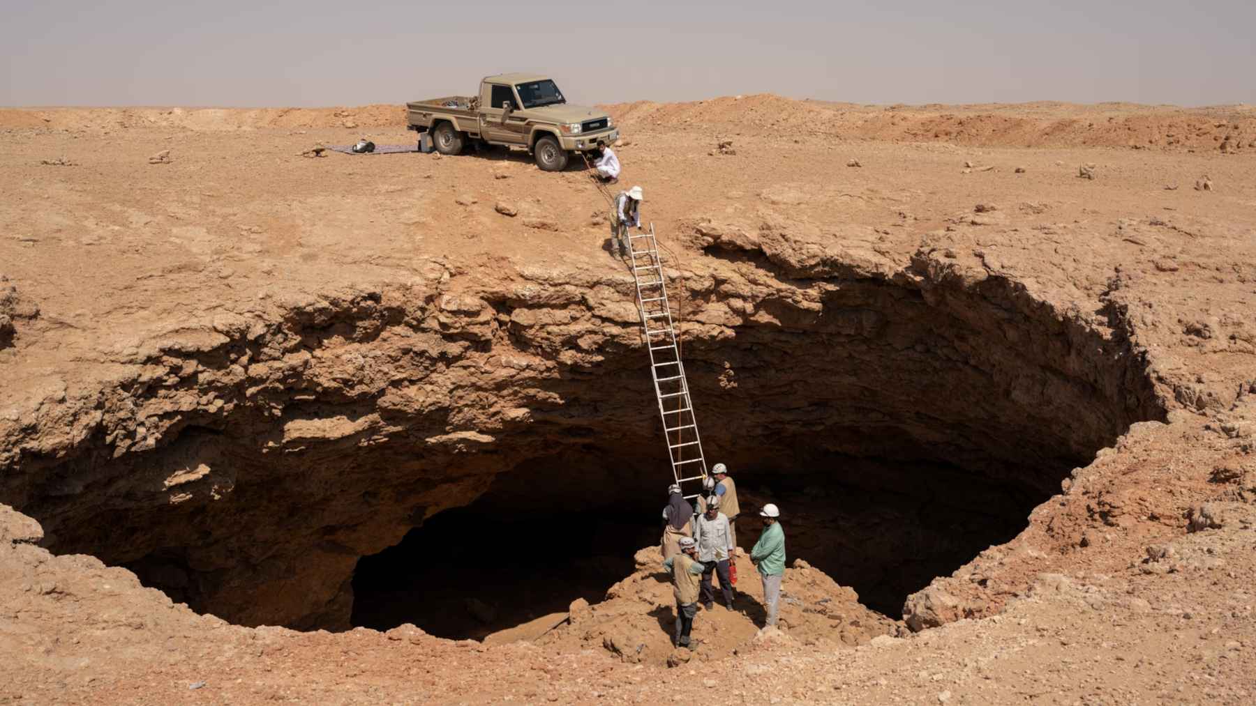 Researchers descending into a desert cave near Arar in northern Saudi Arabia, where naturally cremated cheetah carcasses were found.