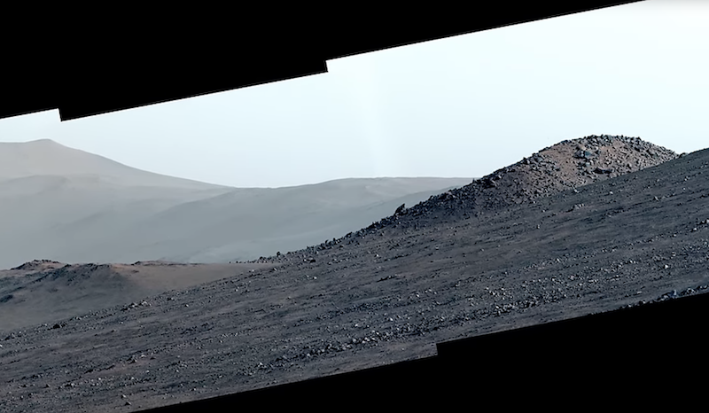 Rubies on Mars: View of a hilly, gravel-covered landscape with mountains in the distance.
