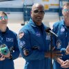 Artemis II crew members - mission specialist Christina Koch (left) and commander Reid Wiseman (right) - listen as pilot Victor Glover speaks to the media after landing at the Kennedy Space Center on March 27, 2026 in Cape Canaveral, Florida. The astronauts' planned 10-day mission will take them around the Moon and back to Earth.